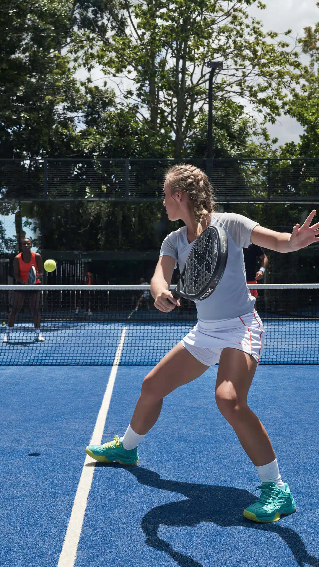 A woman plays padel with friends.