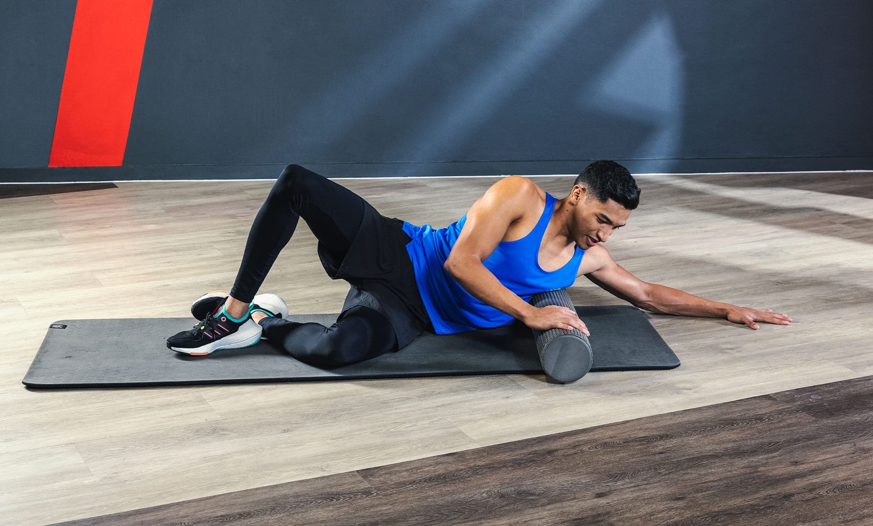 A man exercises on a mat on the gym floor.