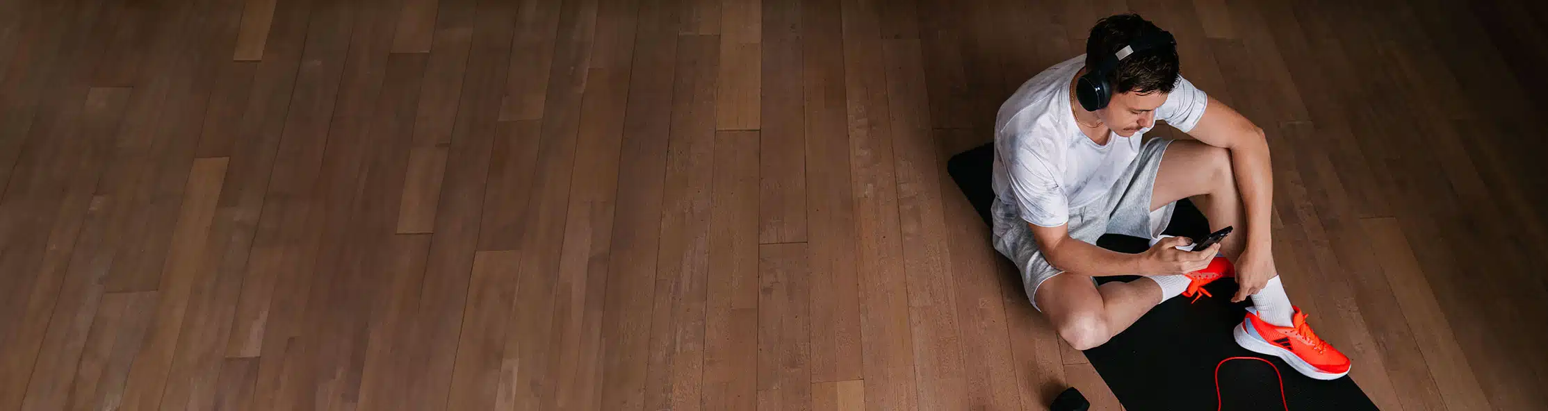 A view of a Virgin Active member siting on the gym floor that's using the Virgin Active app on his phone.